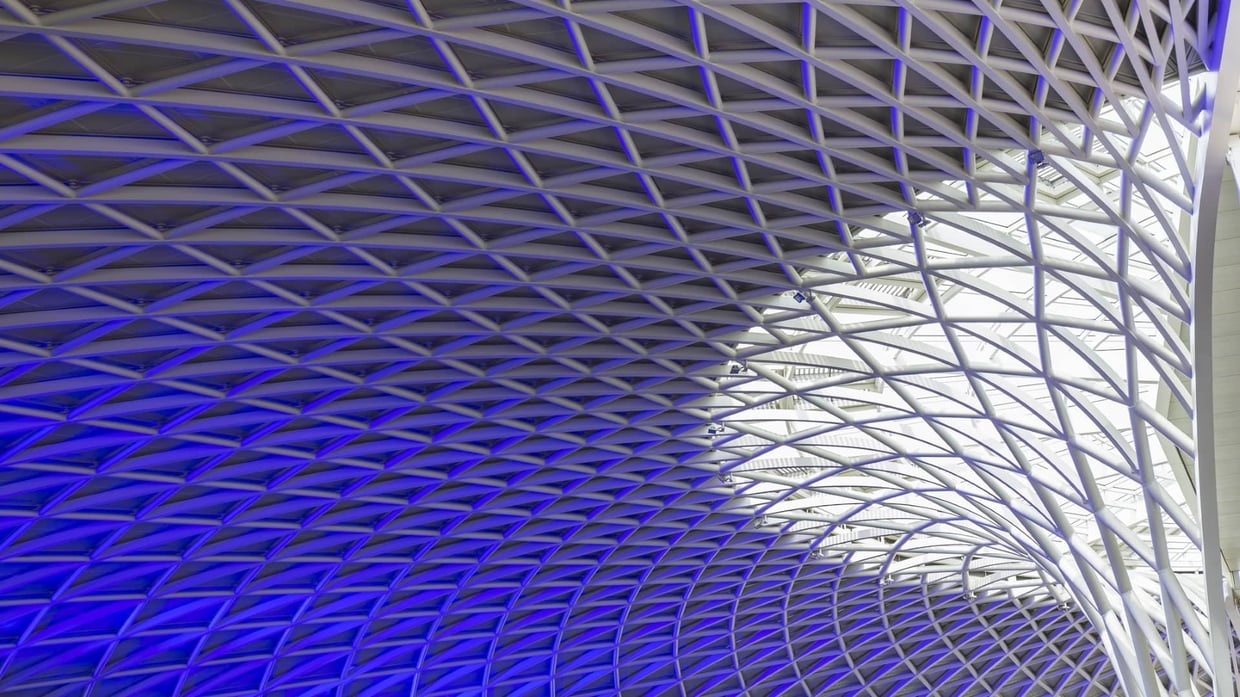 Sun shines through the triangulated roof at Kings Cross Station in London.
