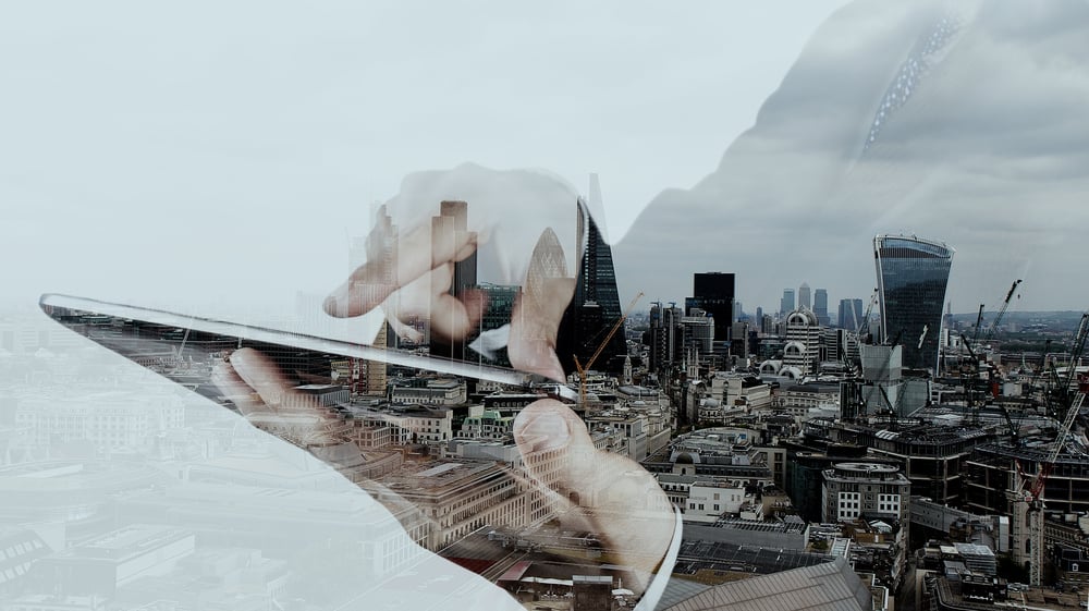 Double exposure of businessman on a tablet and a city background to signify futuristic technology like quantum computing