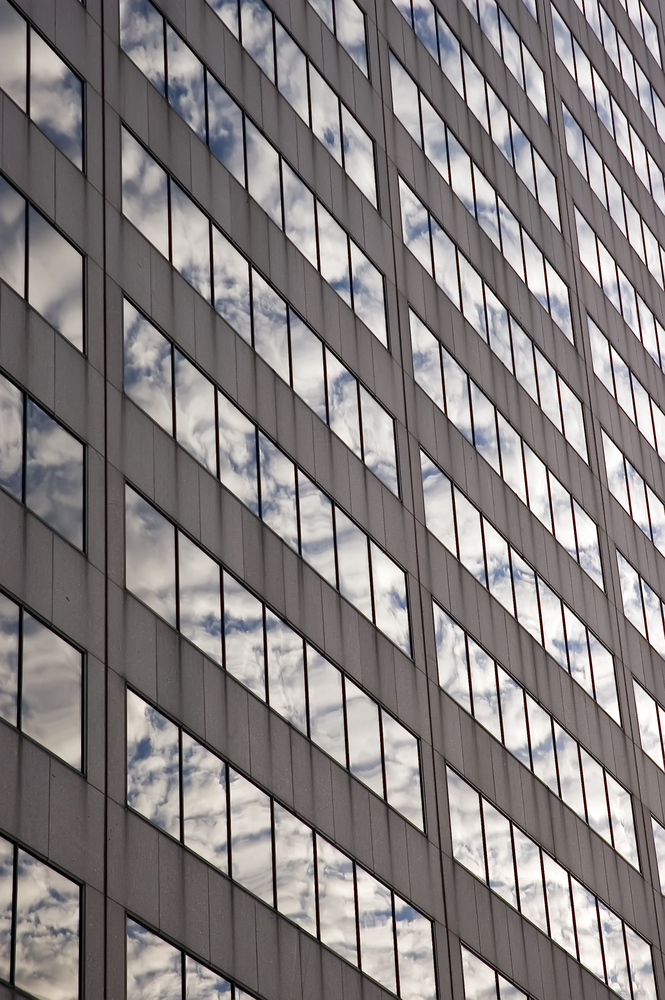 The reflections of clouds in the windows of a skyscraper to signify multiple clouds for our article on why multi-cloud resilience is more challenging than it seems