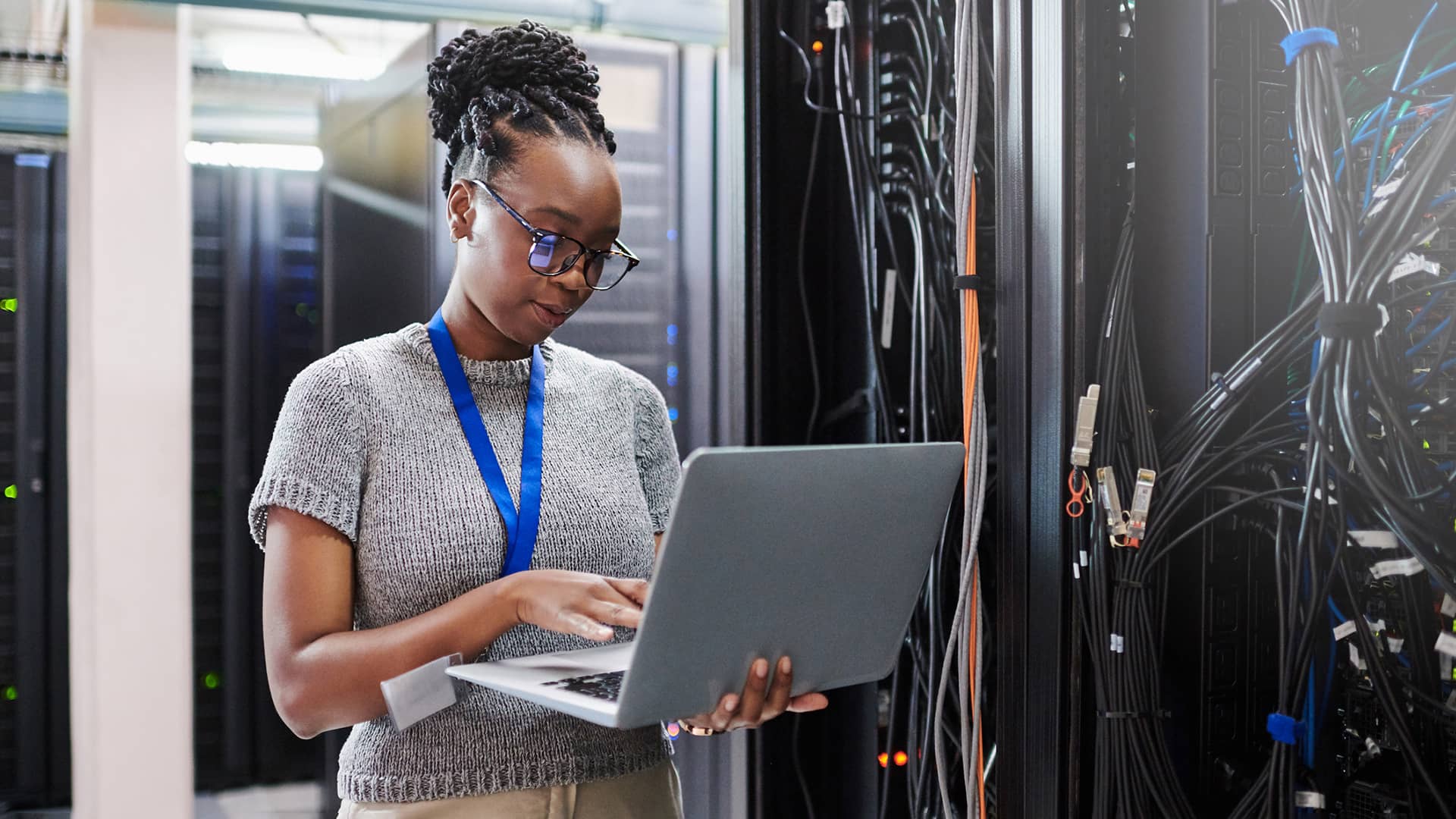 Shot of a young woman using a laptop in a server room